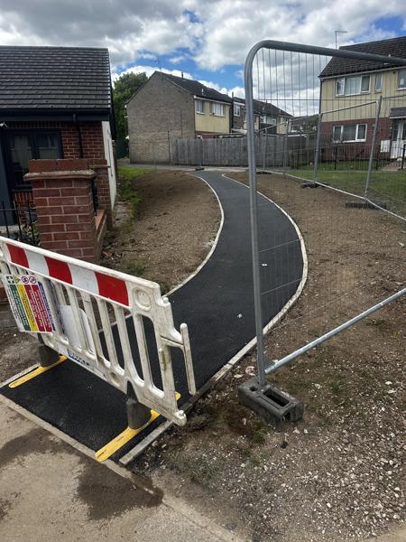Curved tarmac footpath under construction, edged in kerbs