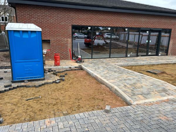 Block-paved path edged with kerbs, beside a new building